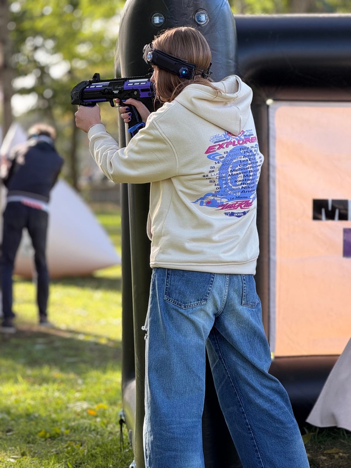 Participante en pleine action lors d'un team building Mission Era en extérieur, visant avec un équipement de jeu