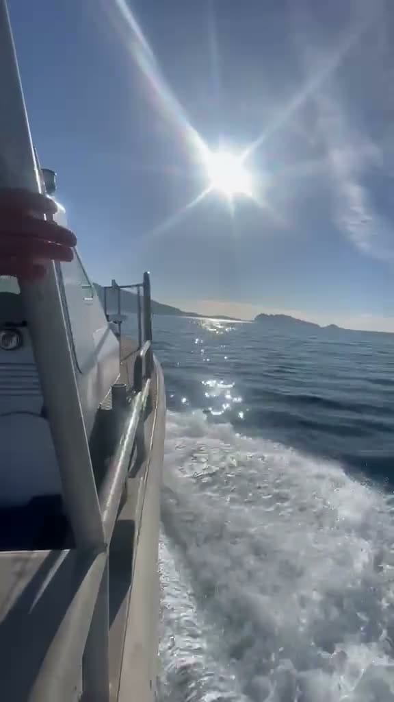 Vue depuis le pont d'un bateau naviguant sur la mer face au soleil, avec le sillage d'écume