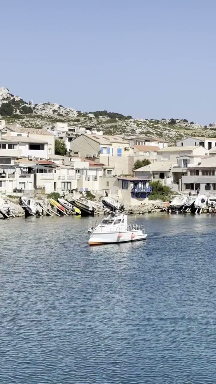 Petit port méditerranéen aux maisons blanches et bateaux de pêche amarrés, près de Marseille.