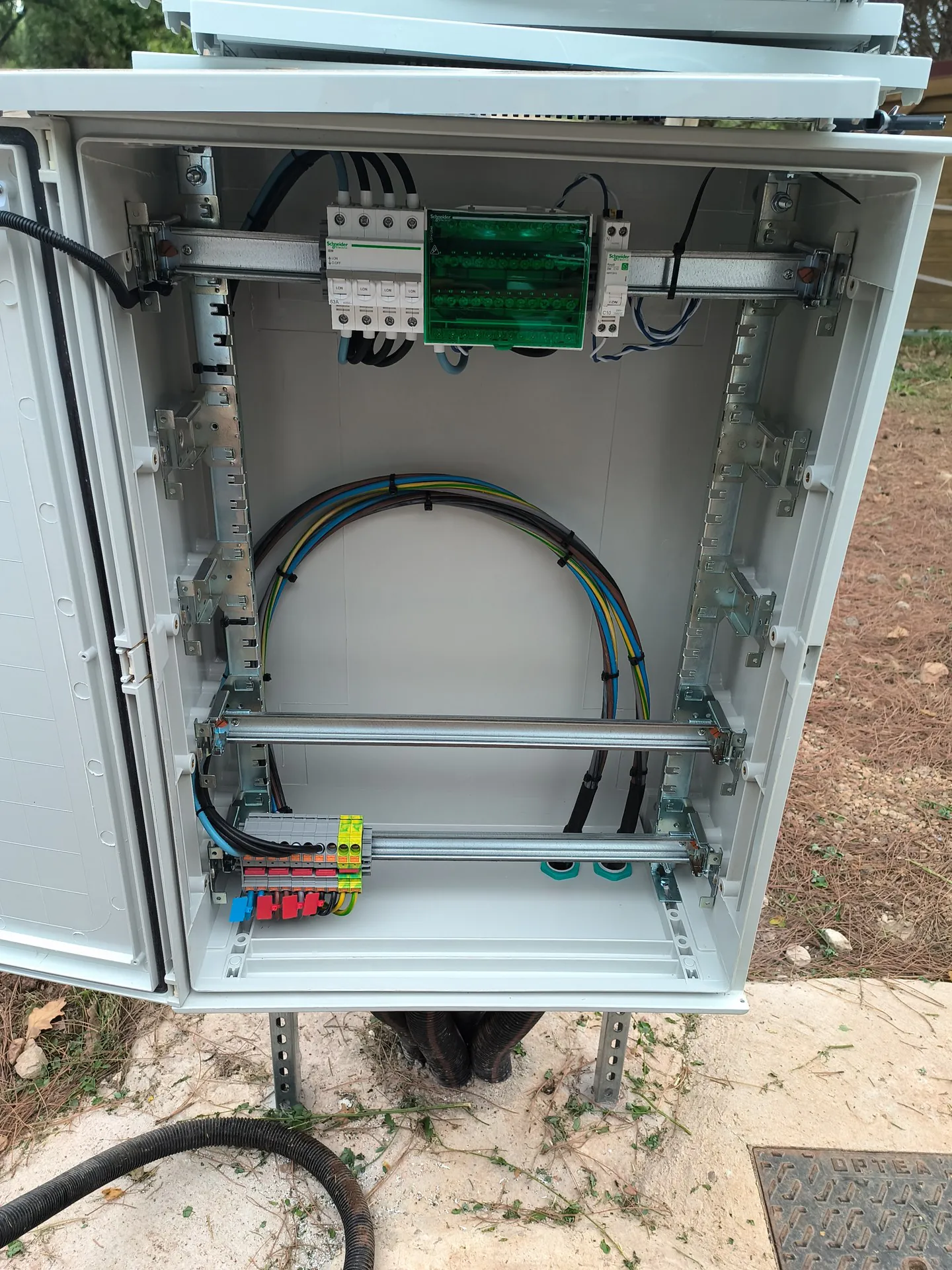 Un coffret électrique extérieur ouvert sur deux montants galvanisés.