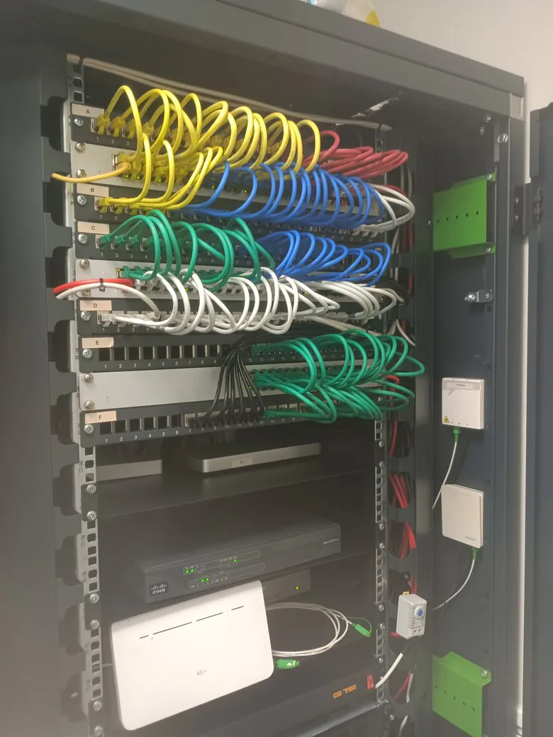 Baie de brassage réseau ouverte, panneaux étiquetés et câbles RJ45 rangés dans un local technique