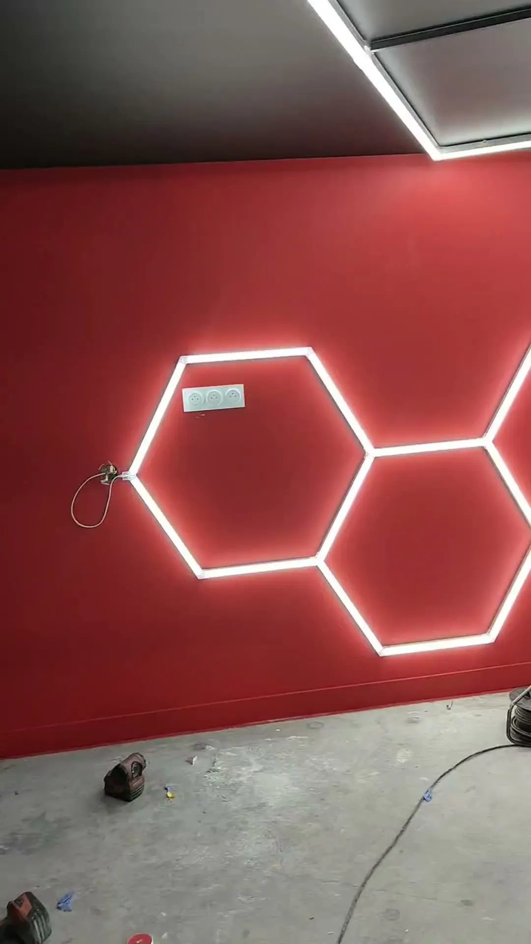Hexagones et cadres lumineux posés au plafond et au mur de salles sombres.
