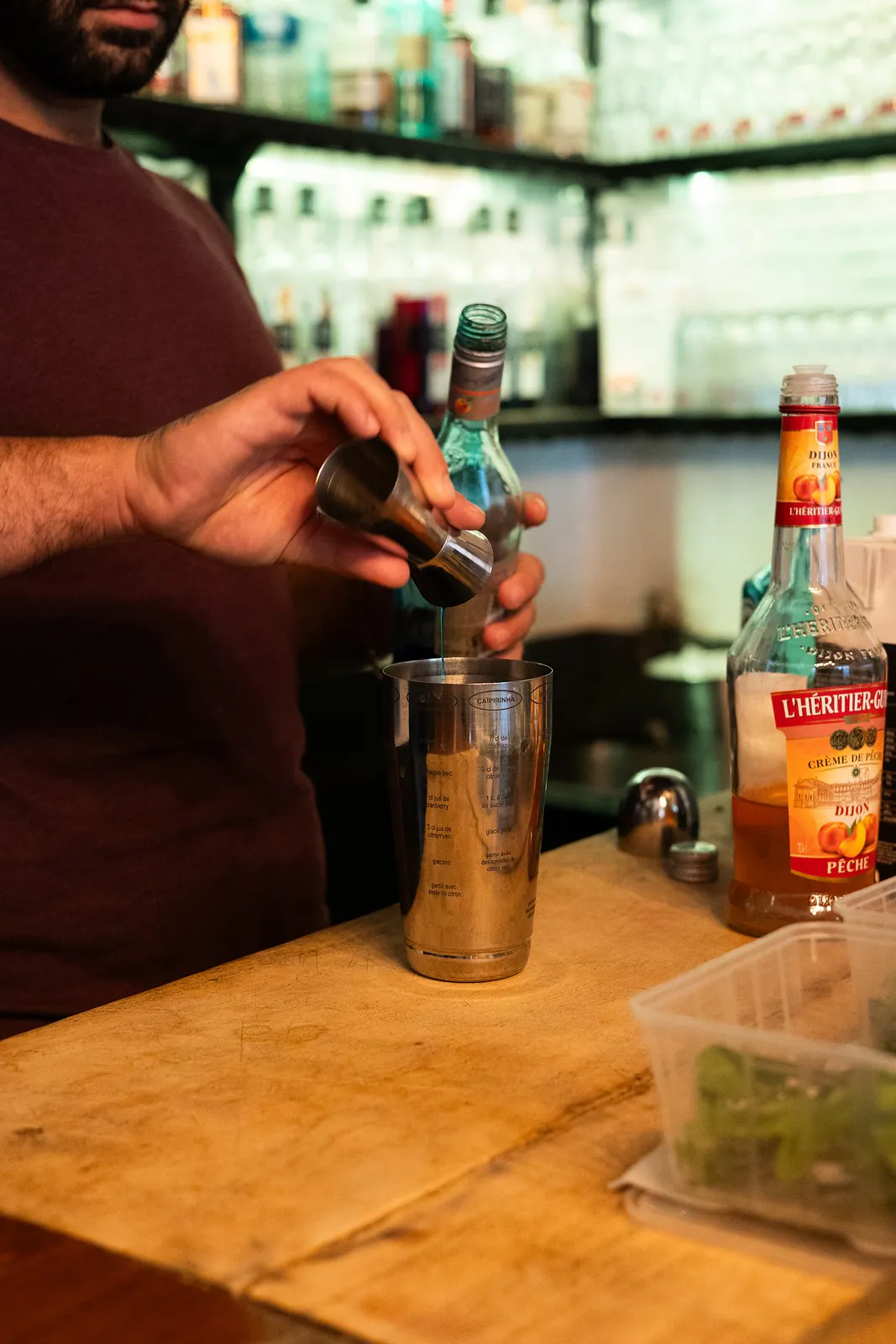 Le barman dose un cocktail au shaker, derrière le comptoir