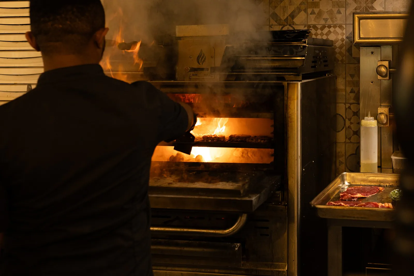 Un cuisinier surveille une cuisson dans le four à braise