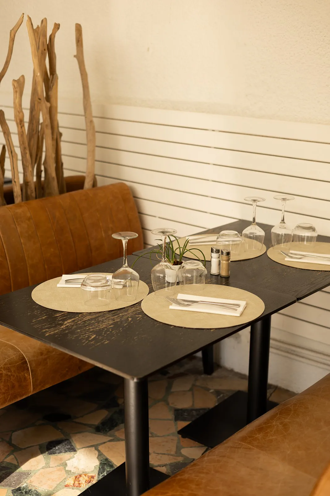 La véranda : banquette cognac, bois flotté et table dressée
