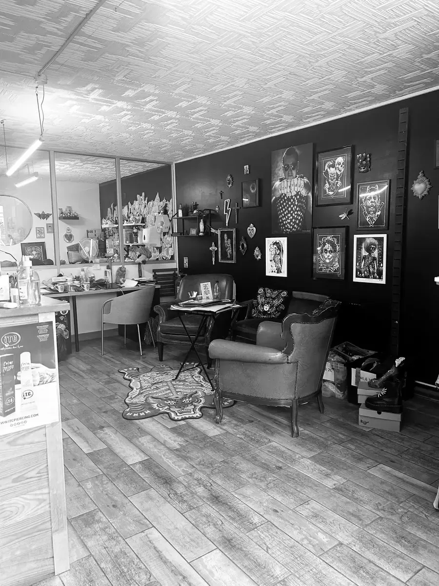 Intérieur du salon : fauteuils en cuir, mur noir et cadres de flashs