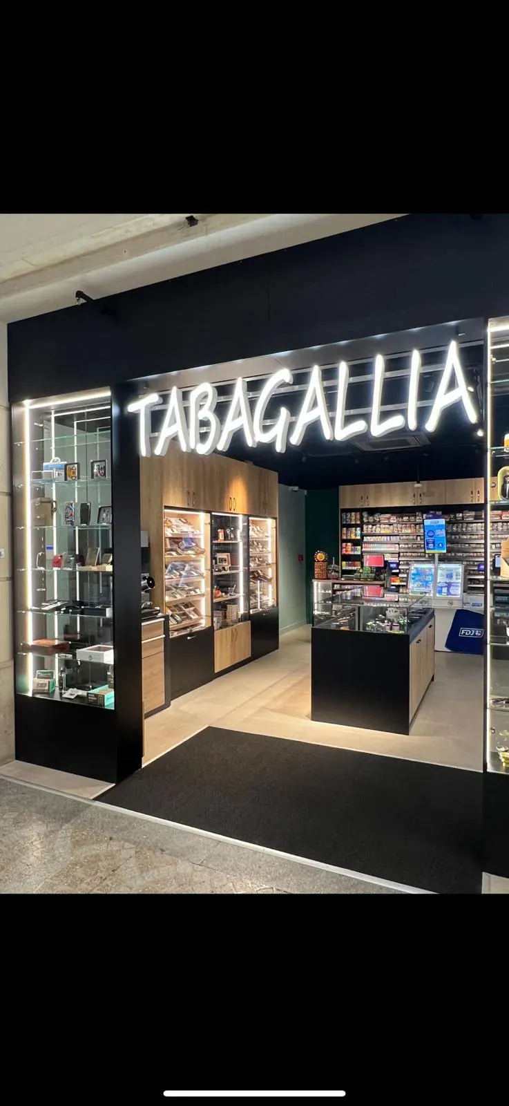 Façade et intérieur d’un magasin de tabac avec enseigne lumineuse et vitrines organisées par univers