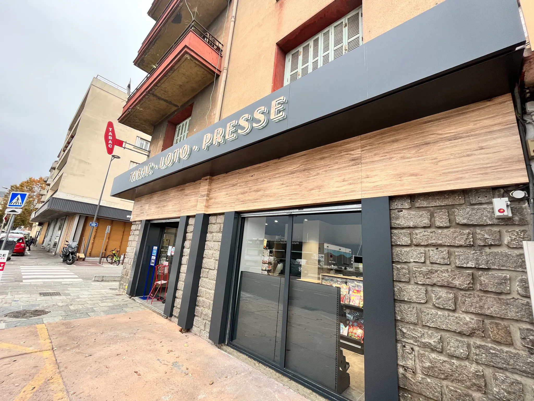 Façade de commerce rénovée avec bardage bois et enseigne sombre