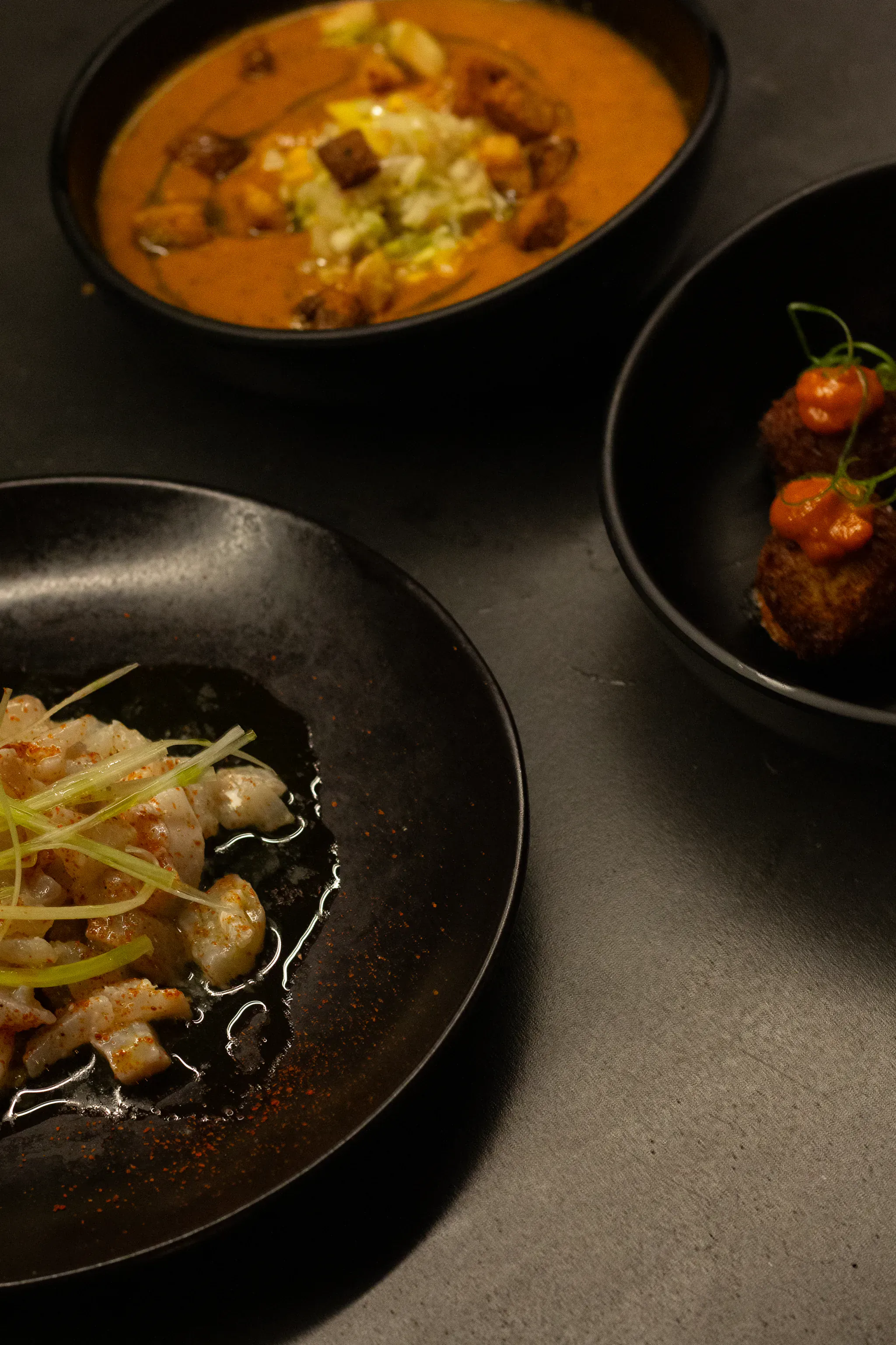 Assiettes noires de cuisine bistronomique créative : ceviche de poisson et curry chez mon amour à Marseille