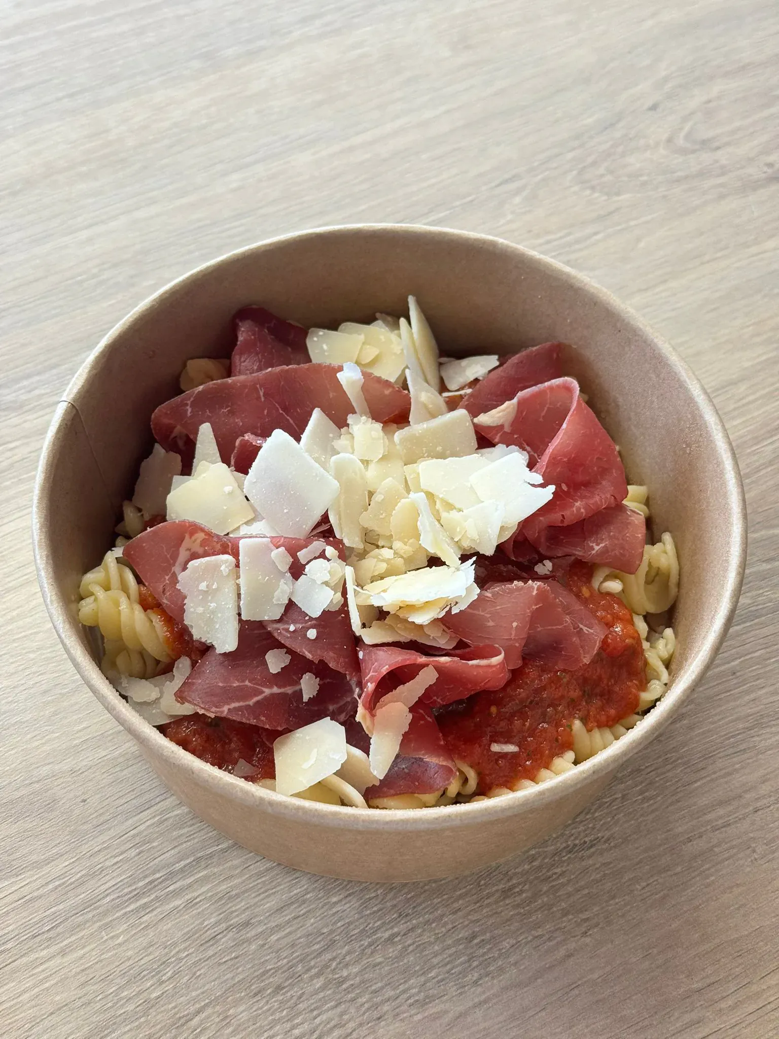 Bol de pâtes à la sauce tomate garni de bœuf séché et copeaux de parmesan, pour une journée de séminaire