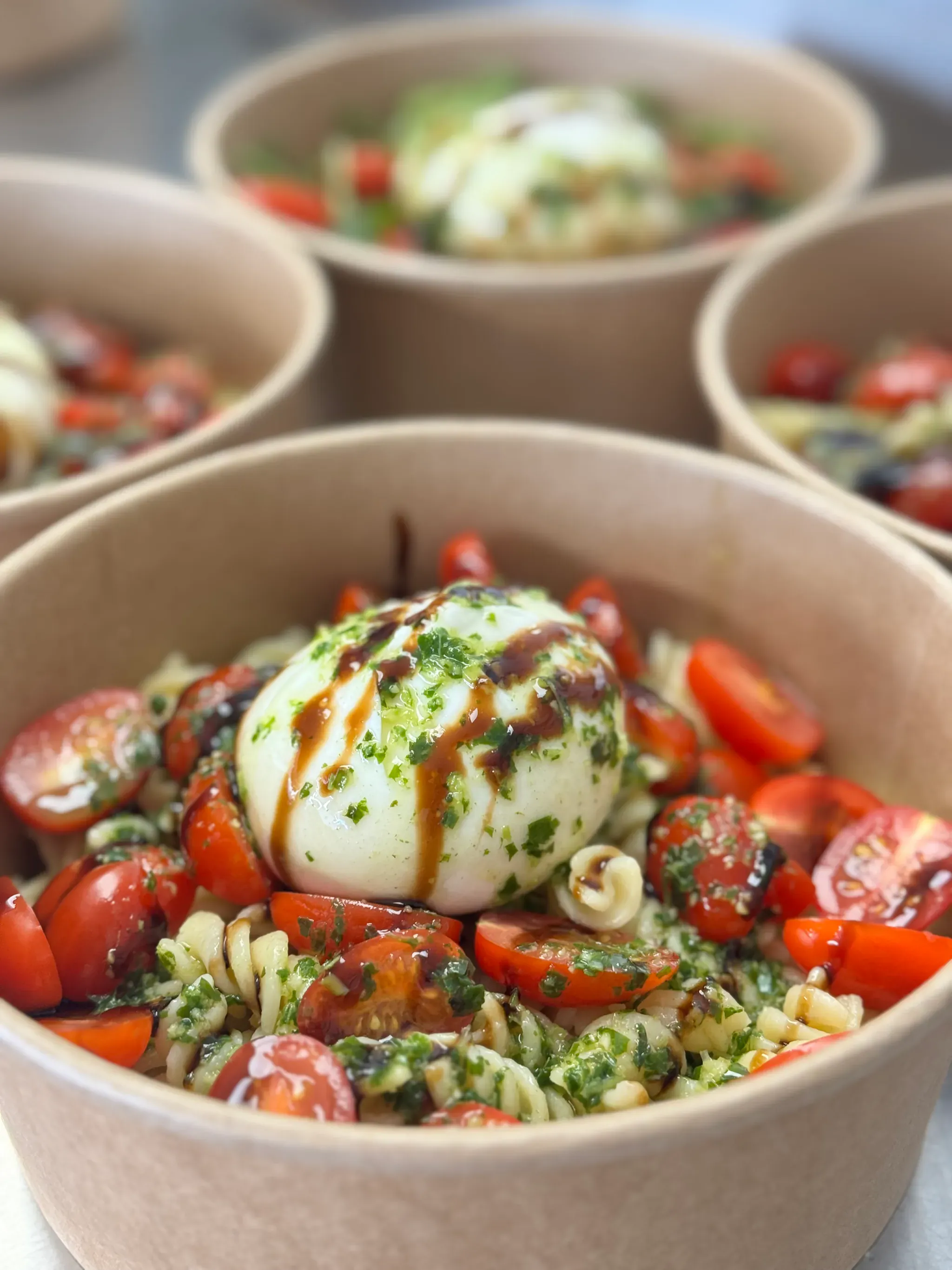 Bols de salade de pâtes aux tomates cerises et burrata, servis lors d'un déjeuner d'équipe