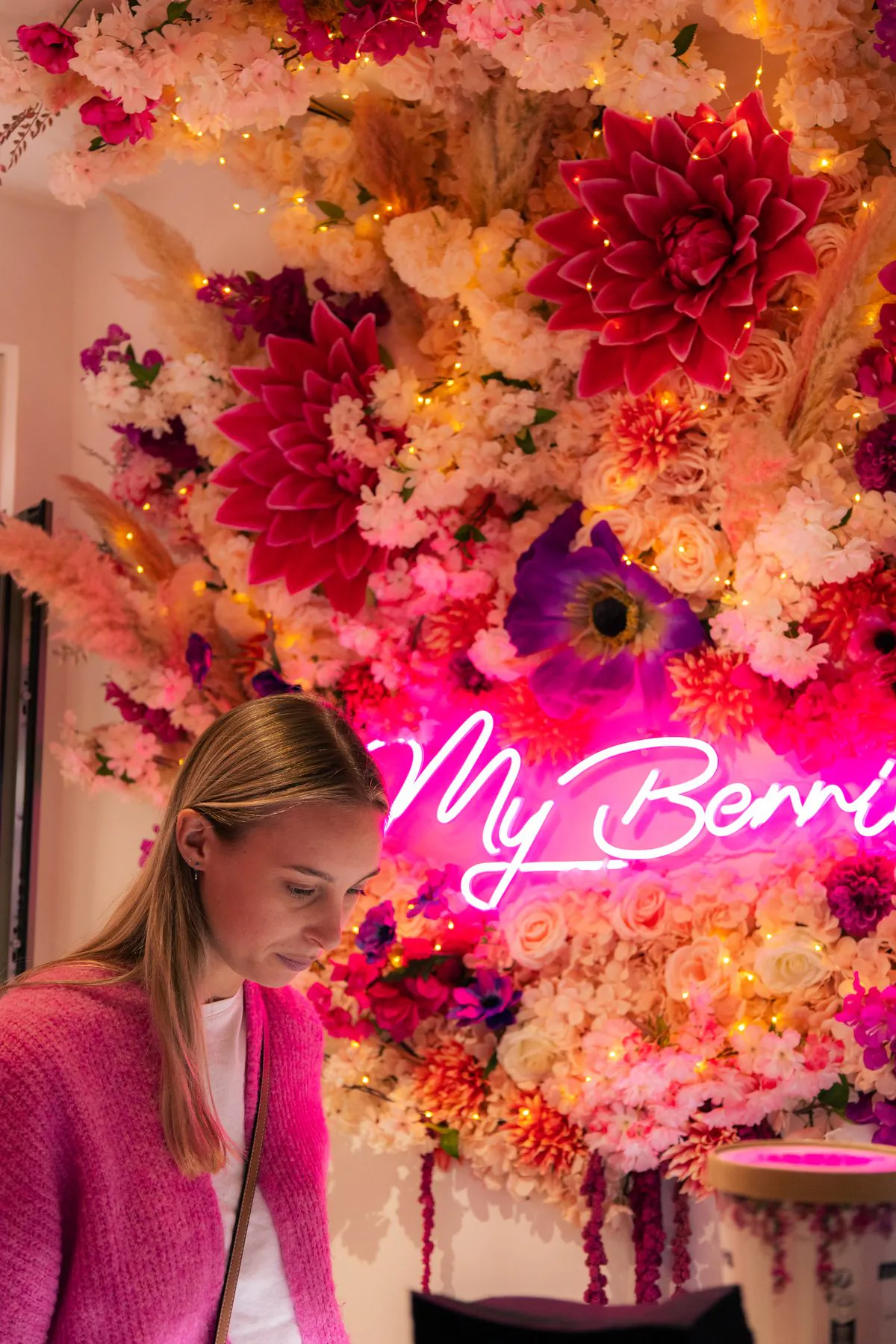 Au comptoir de la boutique, devant le mur de fleurs et le néon My Berries