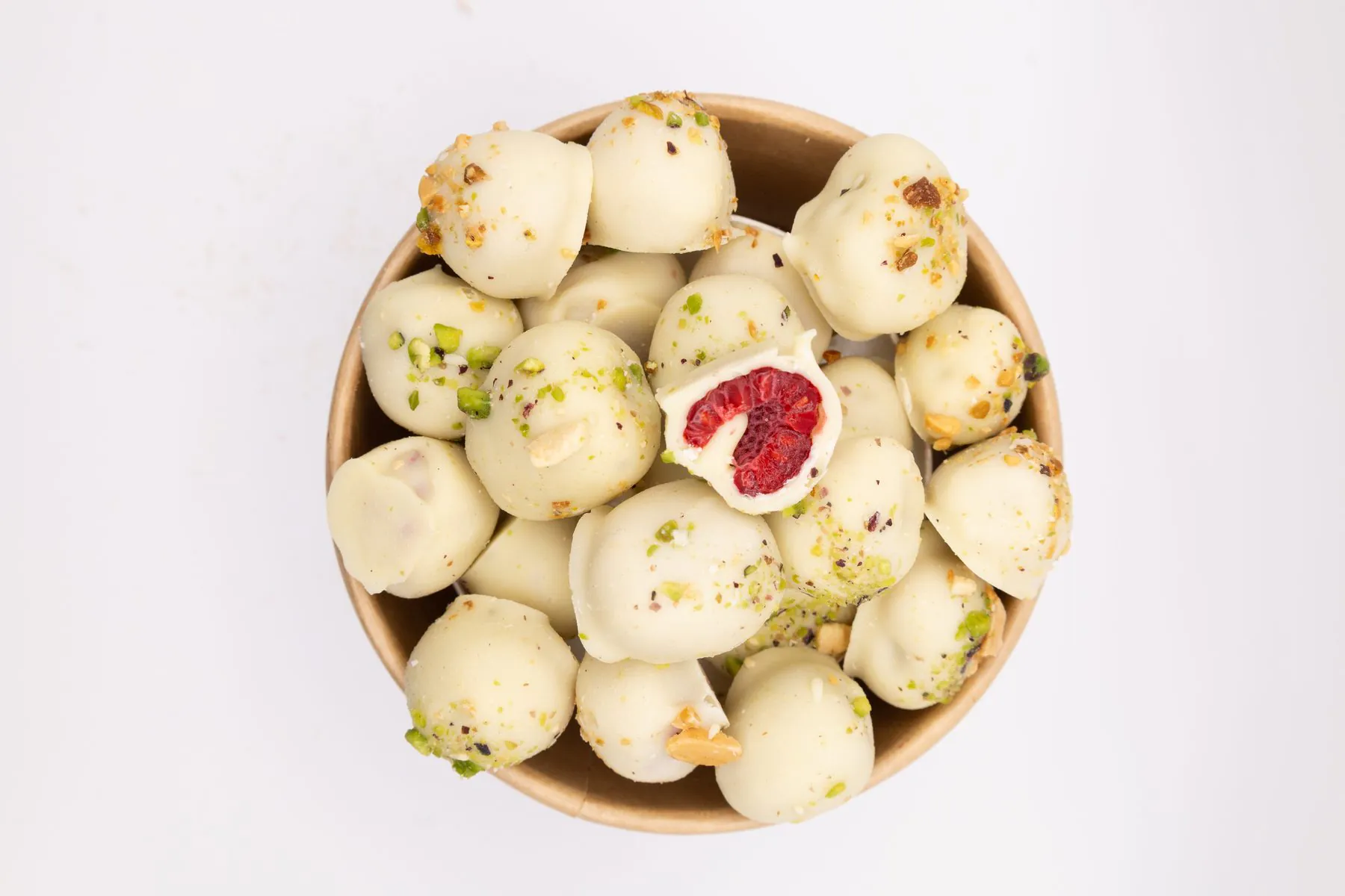 Un pot de framboises enrobées de chocolat blanc et d'éclats, vu du dessus