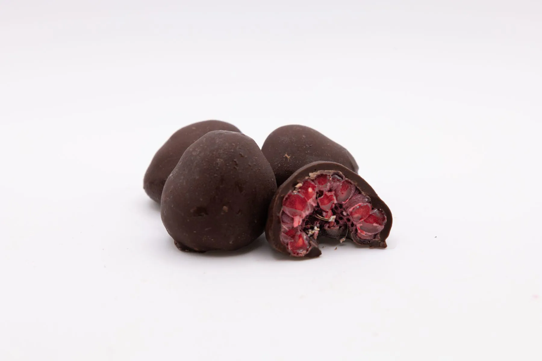 Des framboises enrobées de chocolat noir, dont une coupée en deux