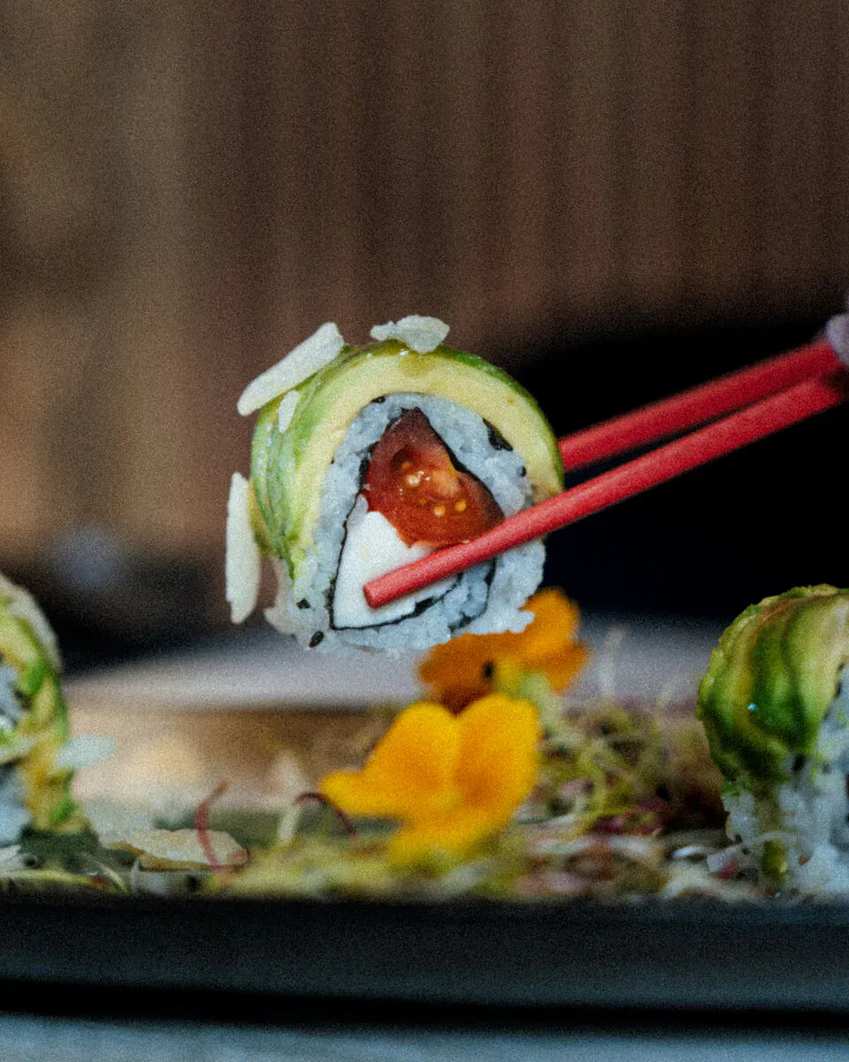 Maki à l'avocat et au saumon saisi entre des baguettes, une option appréciée en buffet