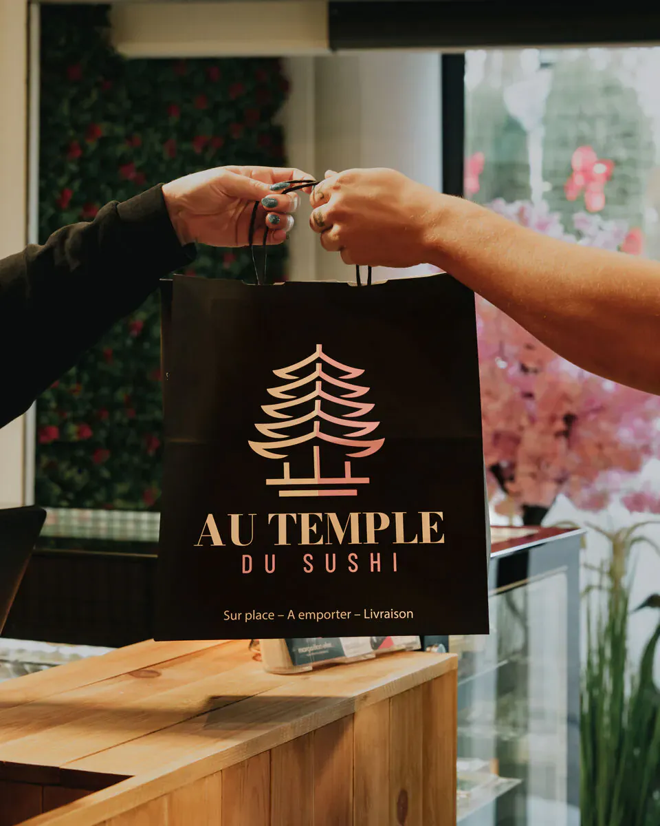 Remise d’un sac à emporter Au Temple du Sushi au comptoir du restaurant
