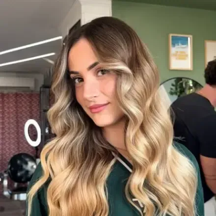 Cliente aux longs cheveux blonds ondulés après un balayage