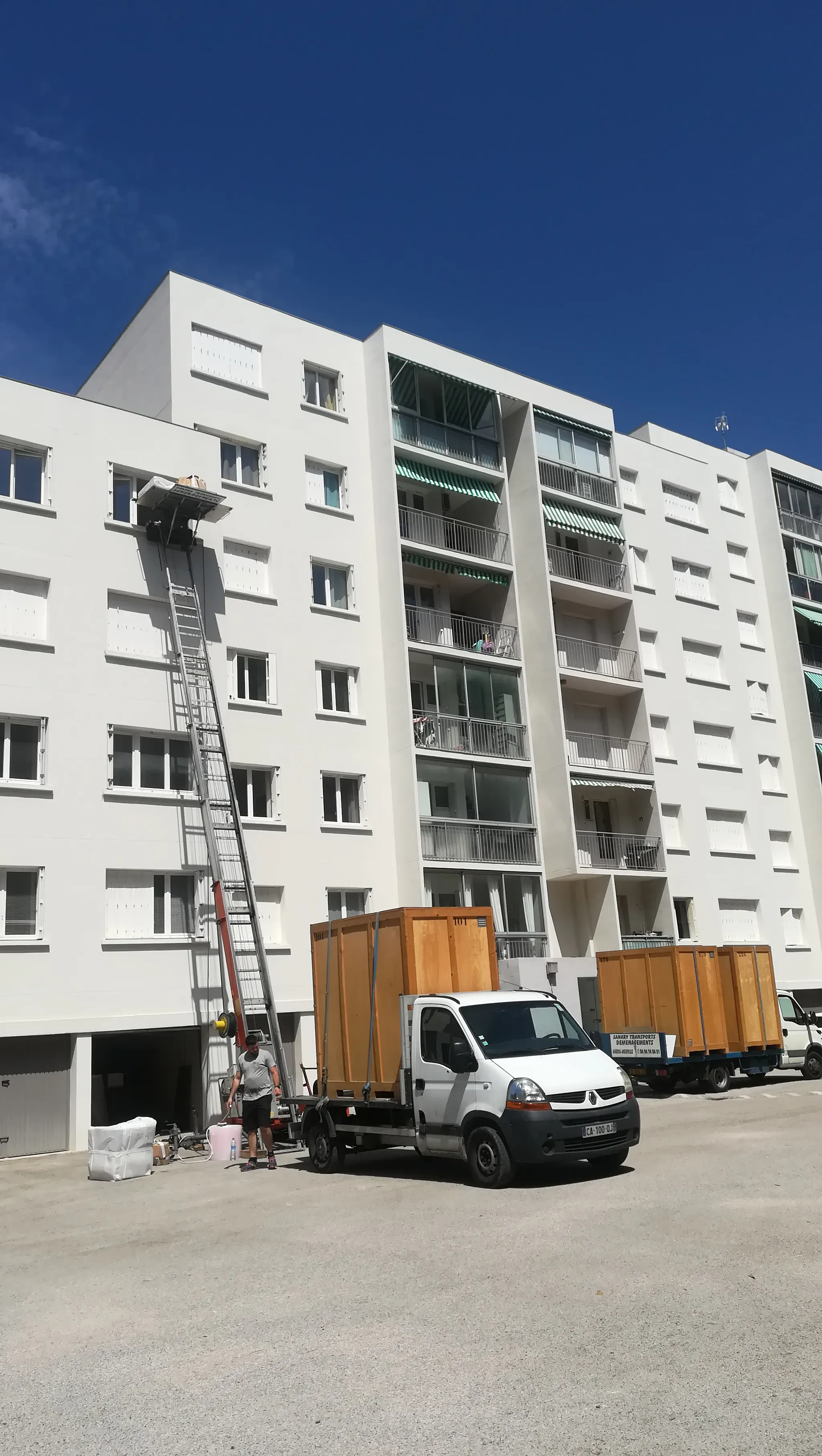 Déménageur hissant des cartons par monte-meuble sur échelle devant un immeuble, comme sur la Croisette
