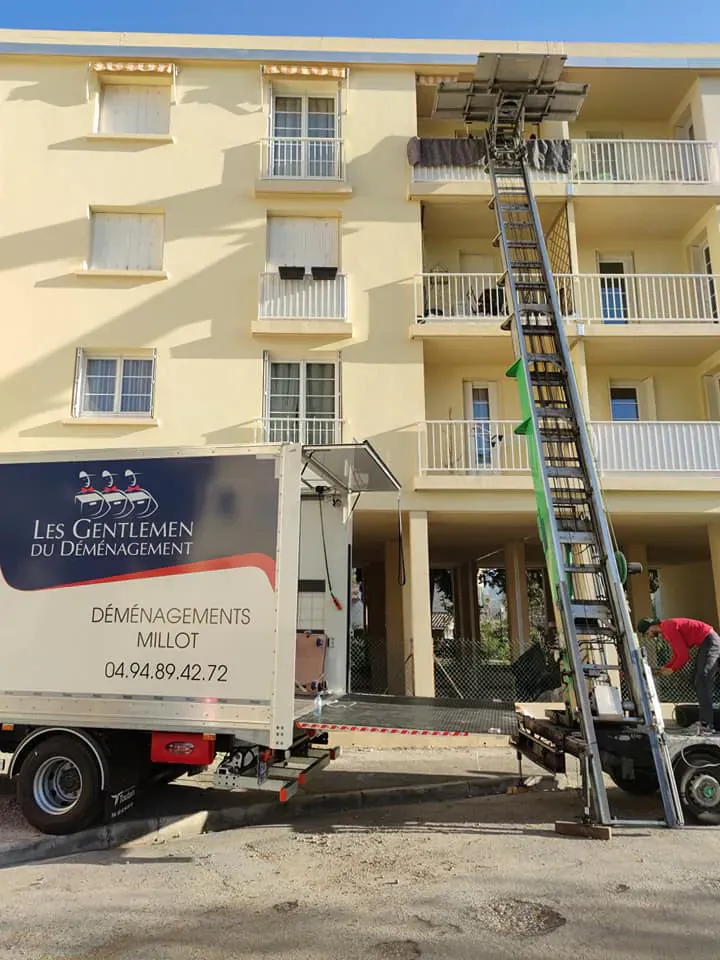 Camion de déménagement et monte-meuble devant un immeuble résidentiel avec ascenseur, nouveau lieu de vie d’un parent âgé