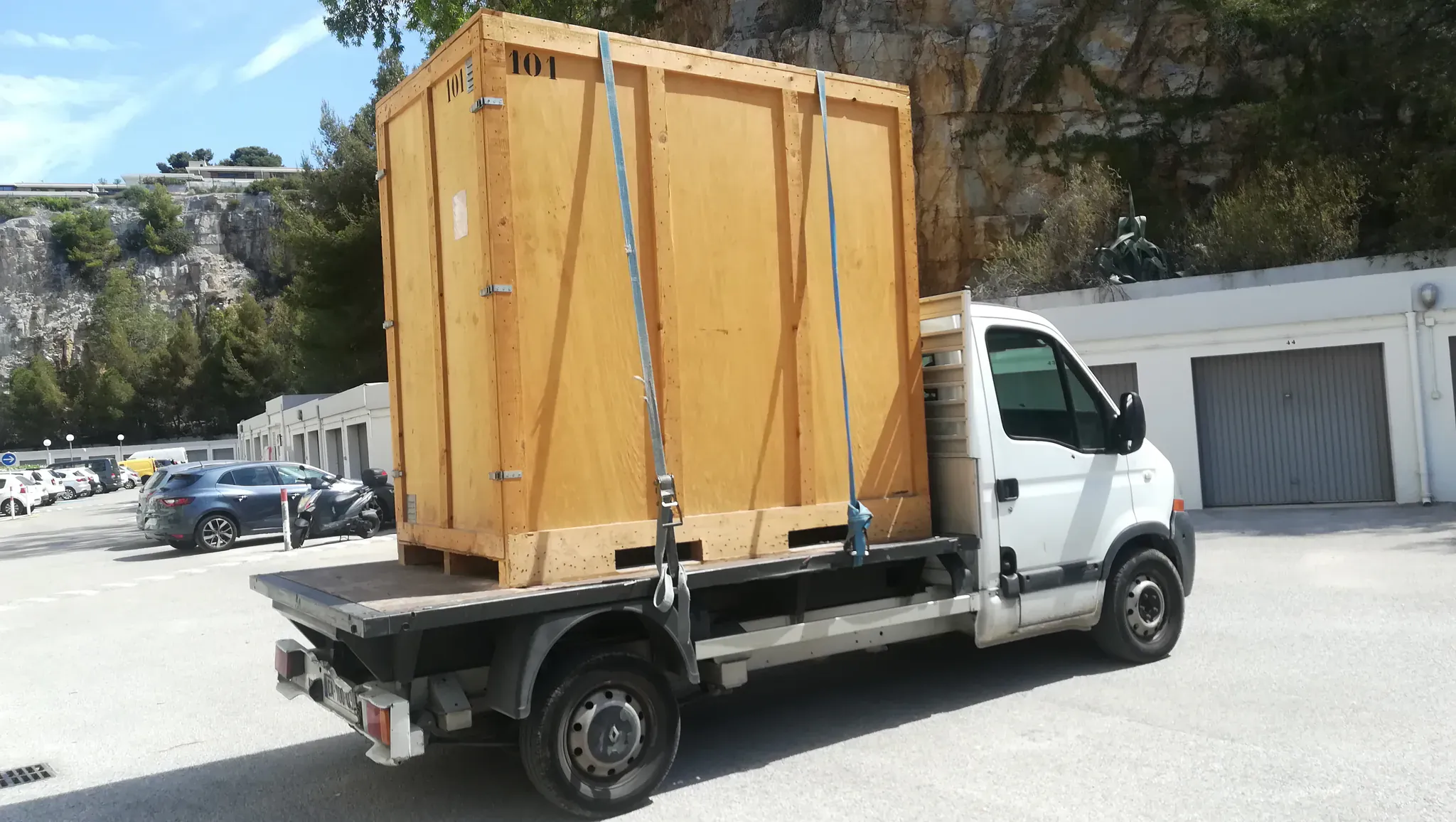 Camion plateau transportant un conteneur de déménagement en bois numéroté et arrimé