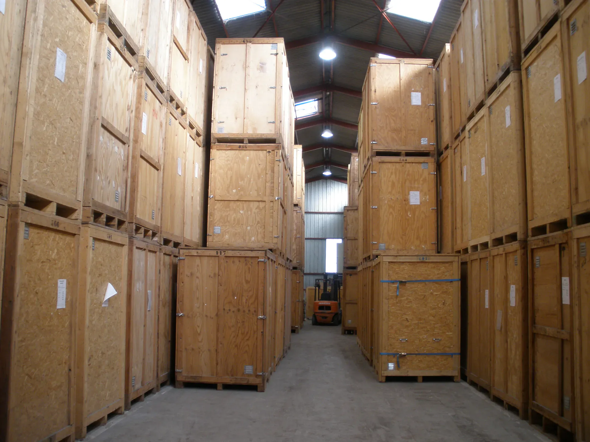 Entrepôt de garde-meuble avec des conteneurs en bois numérotés empilés et un chariot élévateur