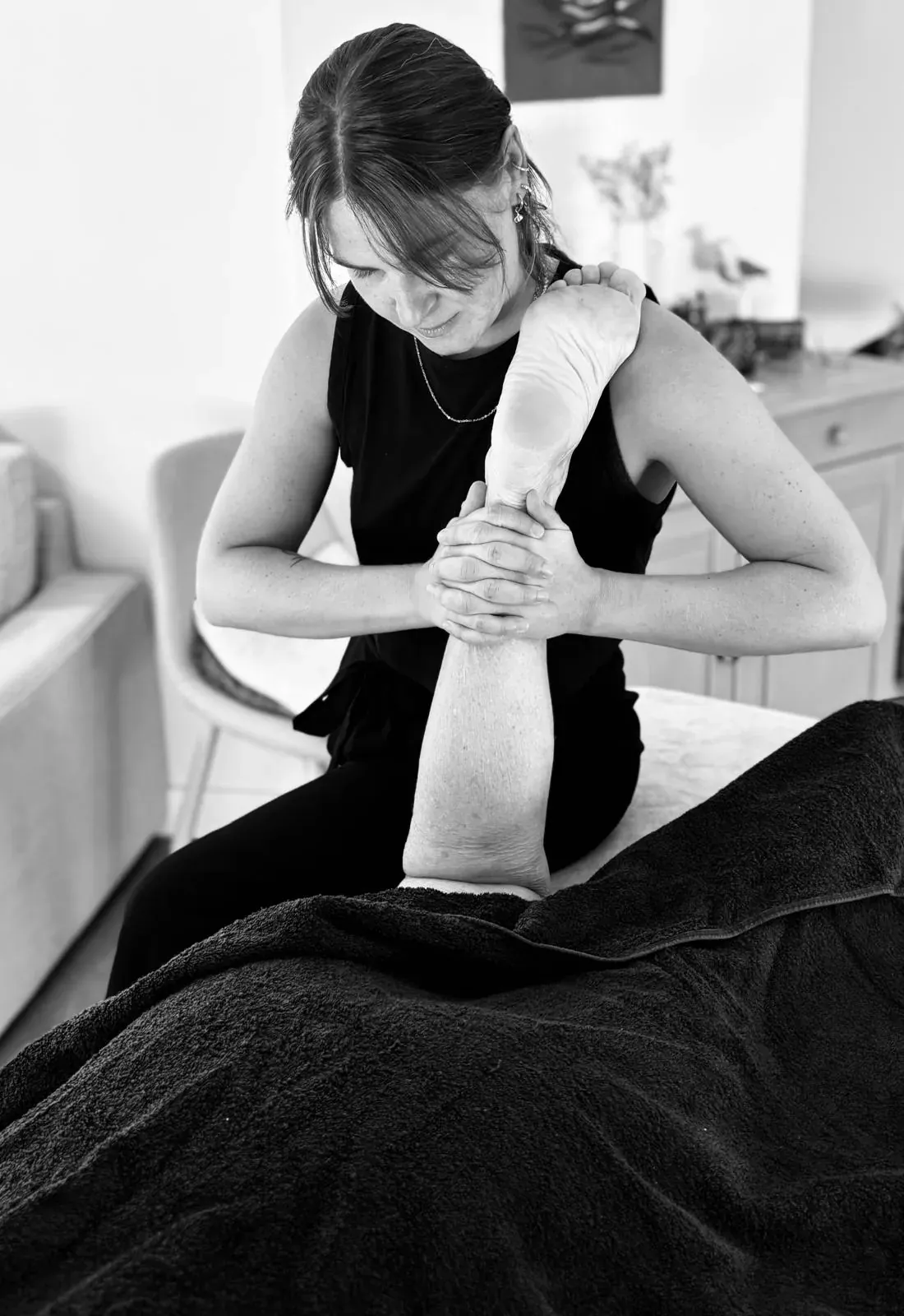 Praticienne mobilisant en douceur la jambe d’une cliente allongée