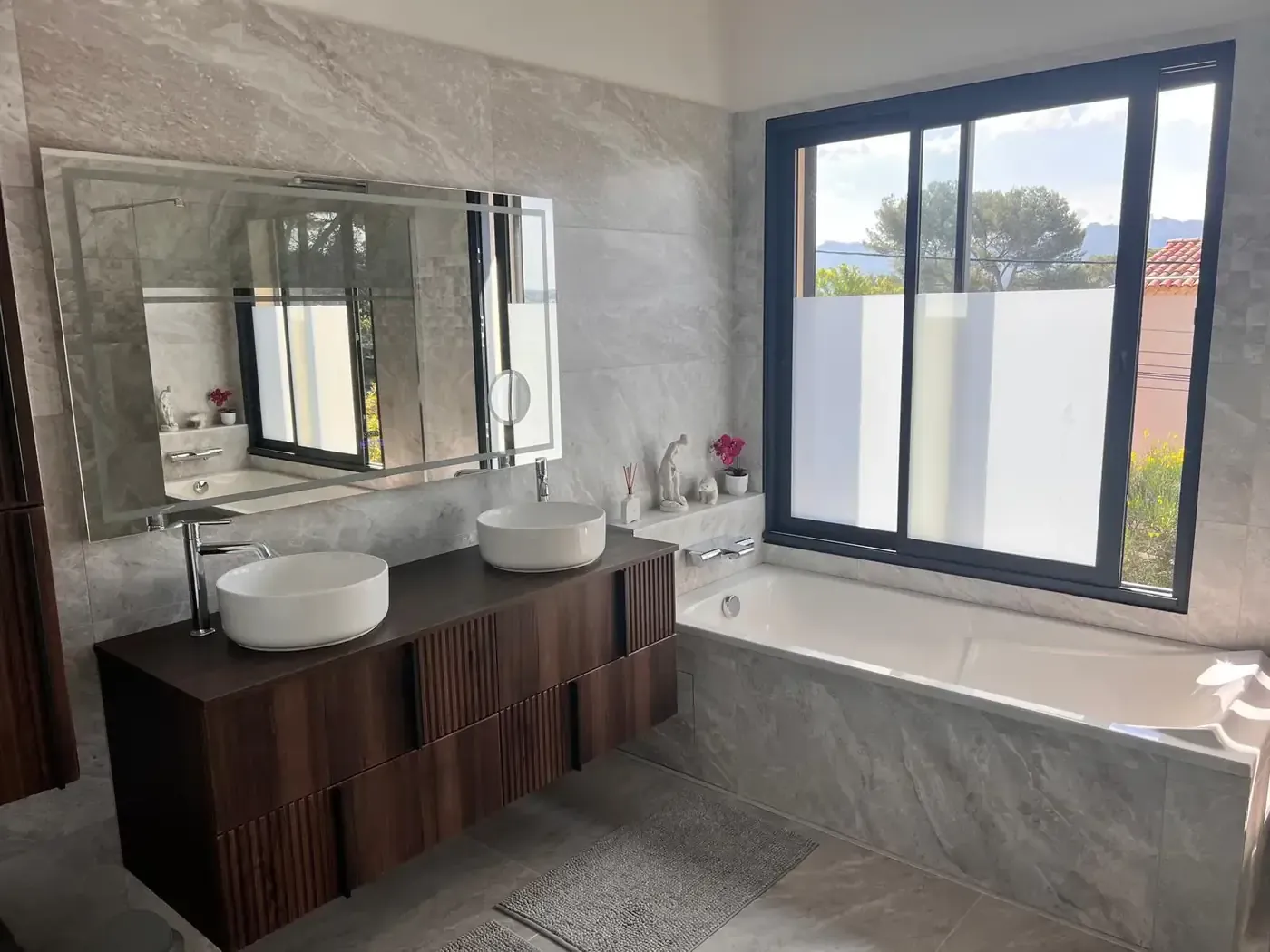 Salle de bain rénovée avec double vasque en bois et baignoire encastrée en marbre