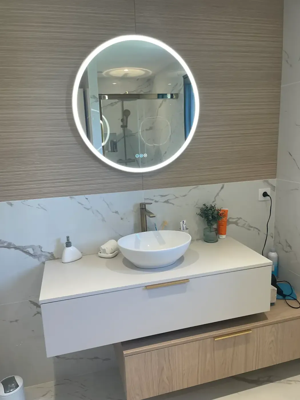 Salle de bain rénovée avec meuble vasque suspendu, miroir rond rétroéclairé et crédence en marbre