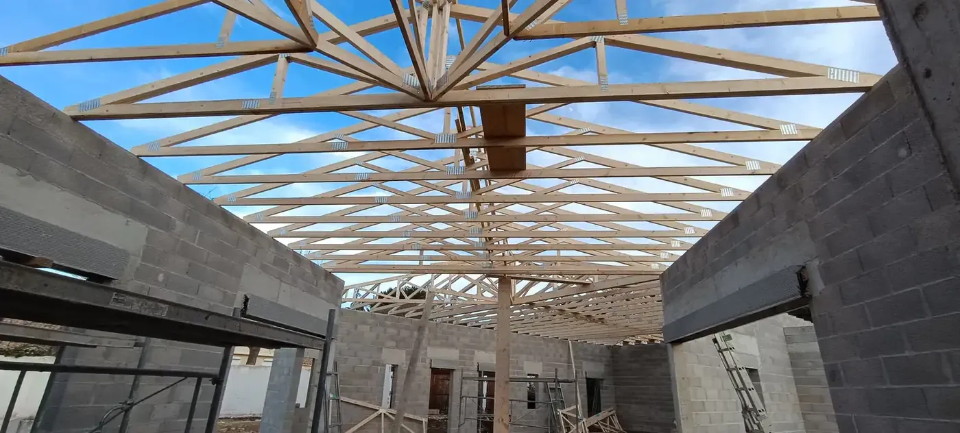 Charpente en bois en cours de pose sur une extension aux murs en parpaings