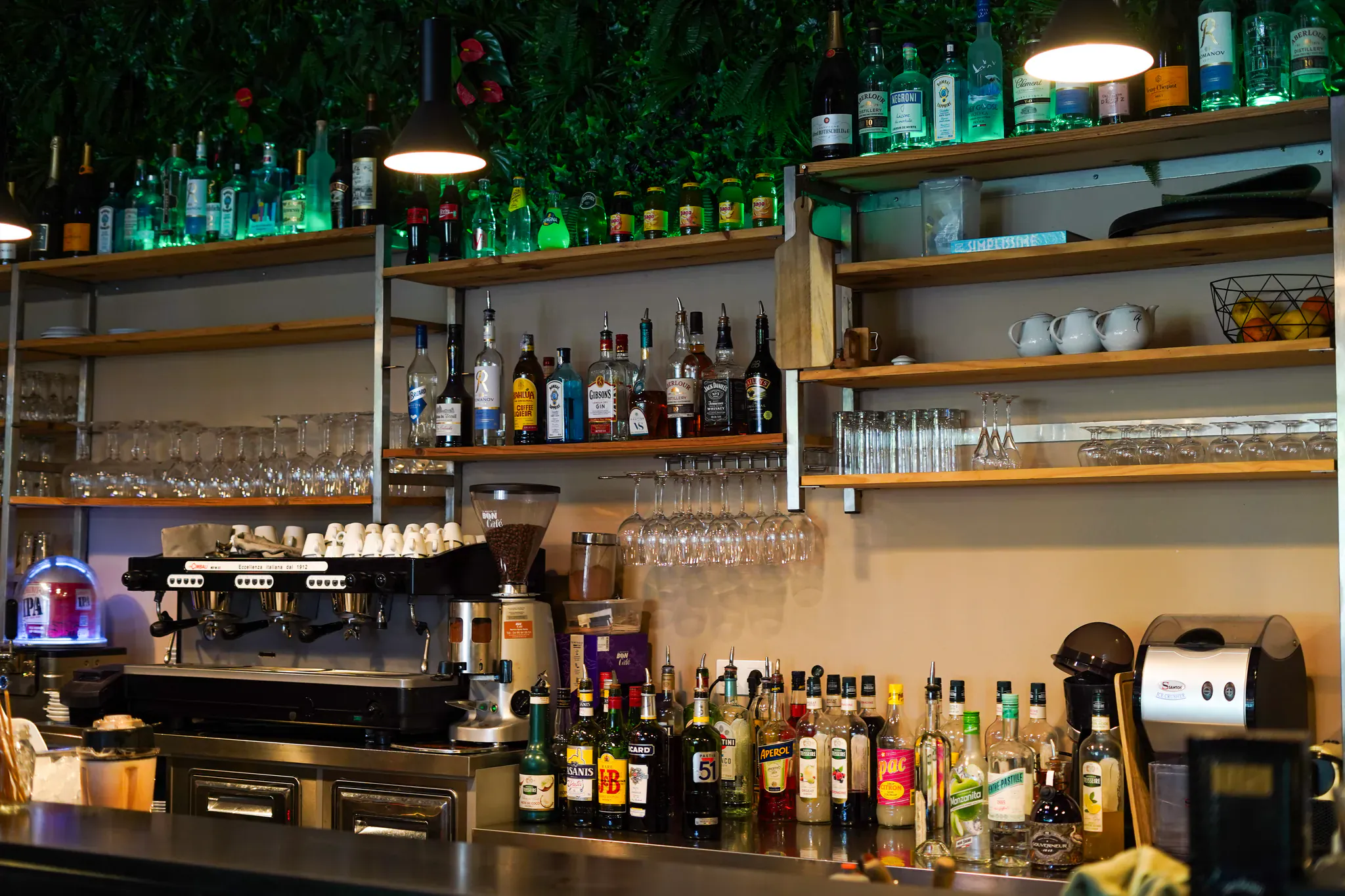 Bar de la Brasserie Le Millésime avec ses bouteilles, verres suspendus et machine à café