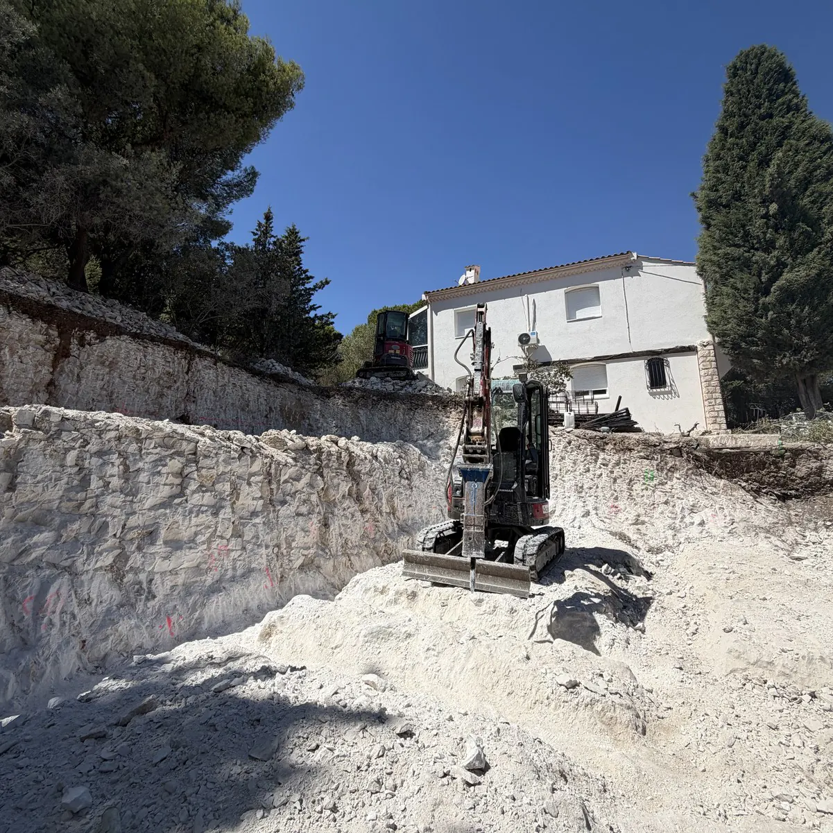 Mini-pelle dans une fouille creusée dans la roche
