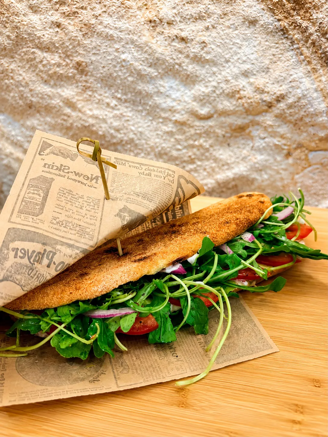 Sandwich baguette garni de roquette, tomates cerises et oignons rouges