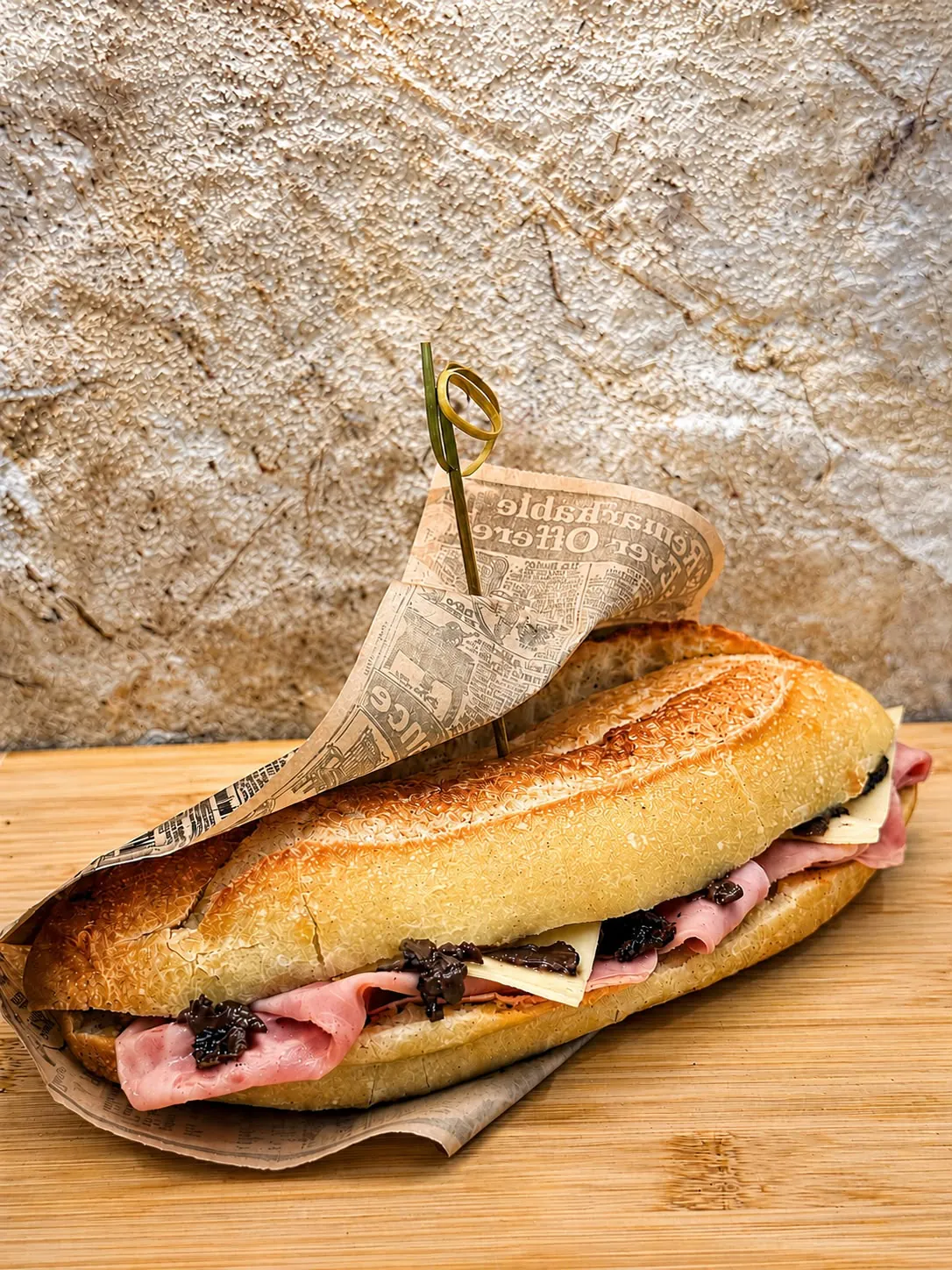 Sandwich baguette garni de jambon, fromage et olives noires, prêt à composer un plateau de séminaire