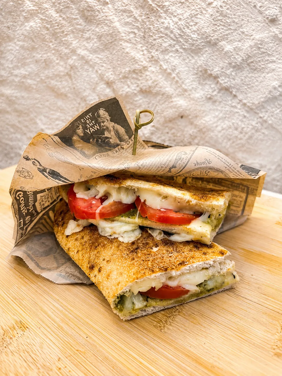 Sandwich grillé coupé en deux, garni de tomates fraîches, mozzarella fondue et pesto, en version buffet