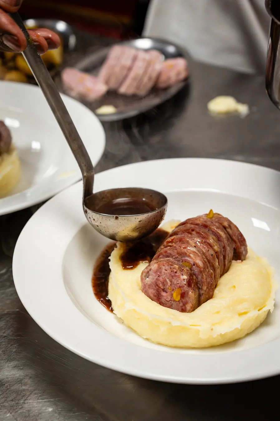 Vigneronne sauce ladled over the hot sausage and its mashed potatoes