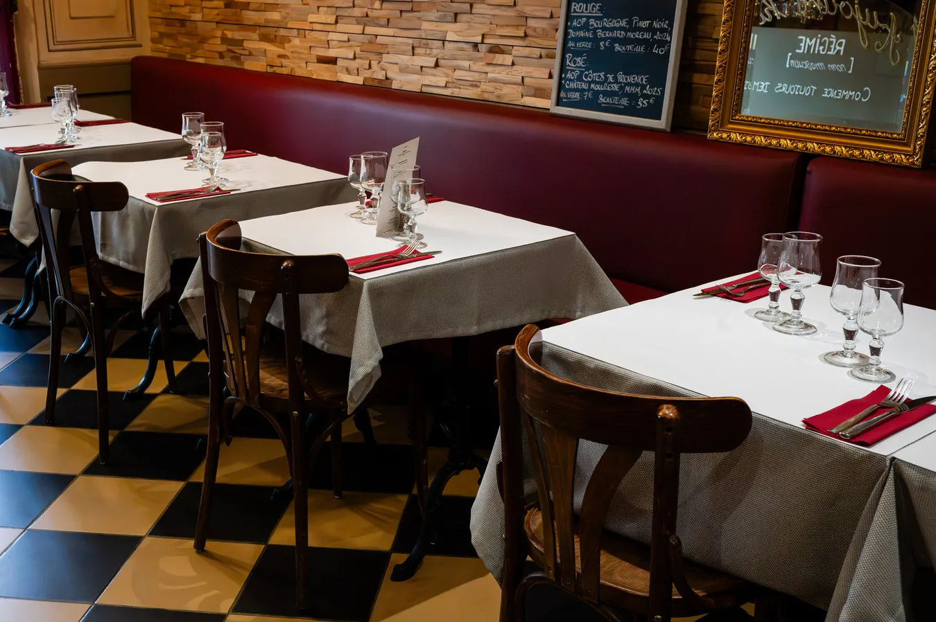 The ground-floor room: chequered floor, burgundy banquette, stone wall and slate boards