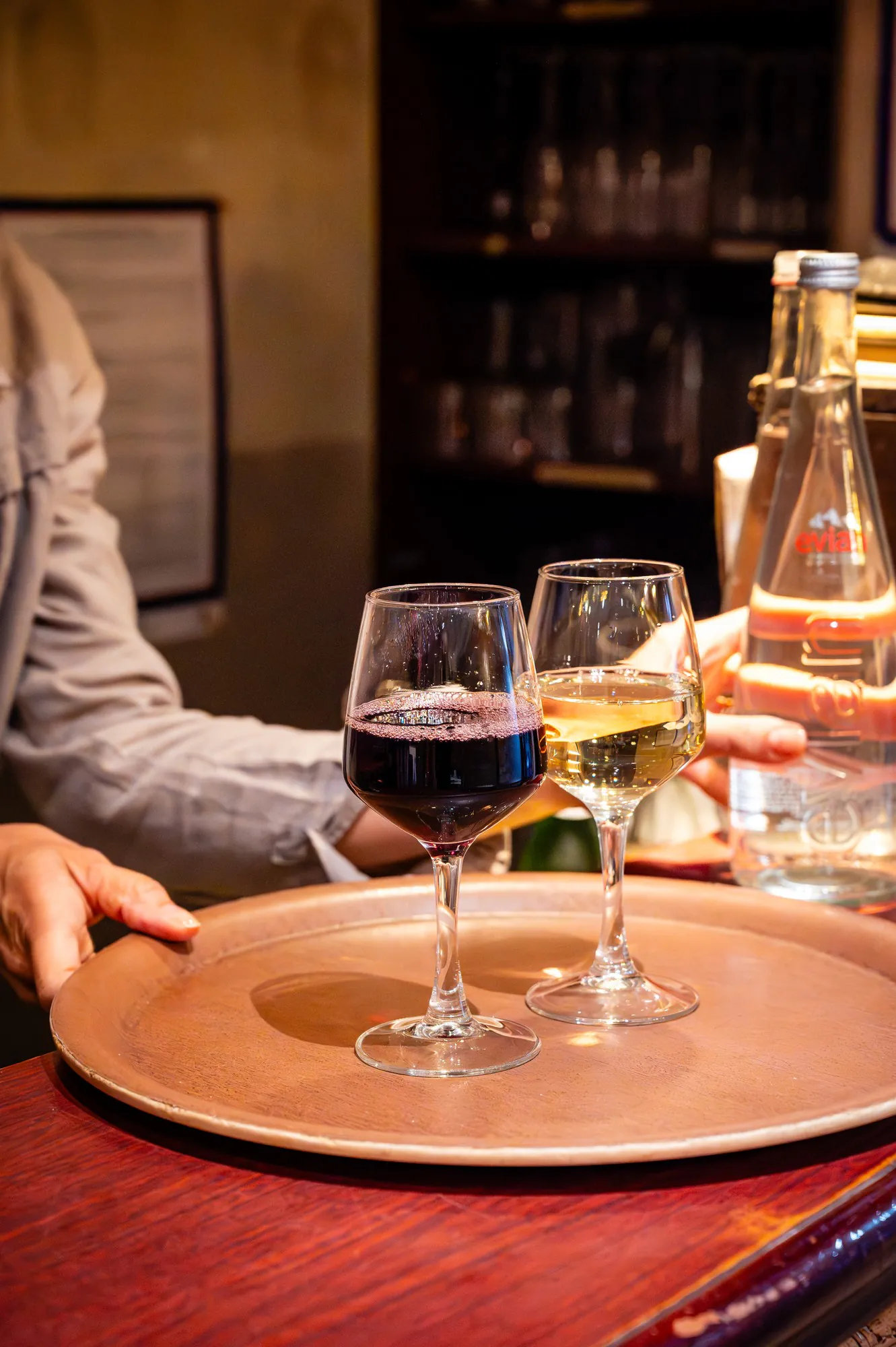Un verre de rouge et un verre de blanc apportés sur un plateau