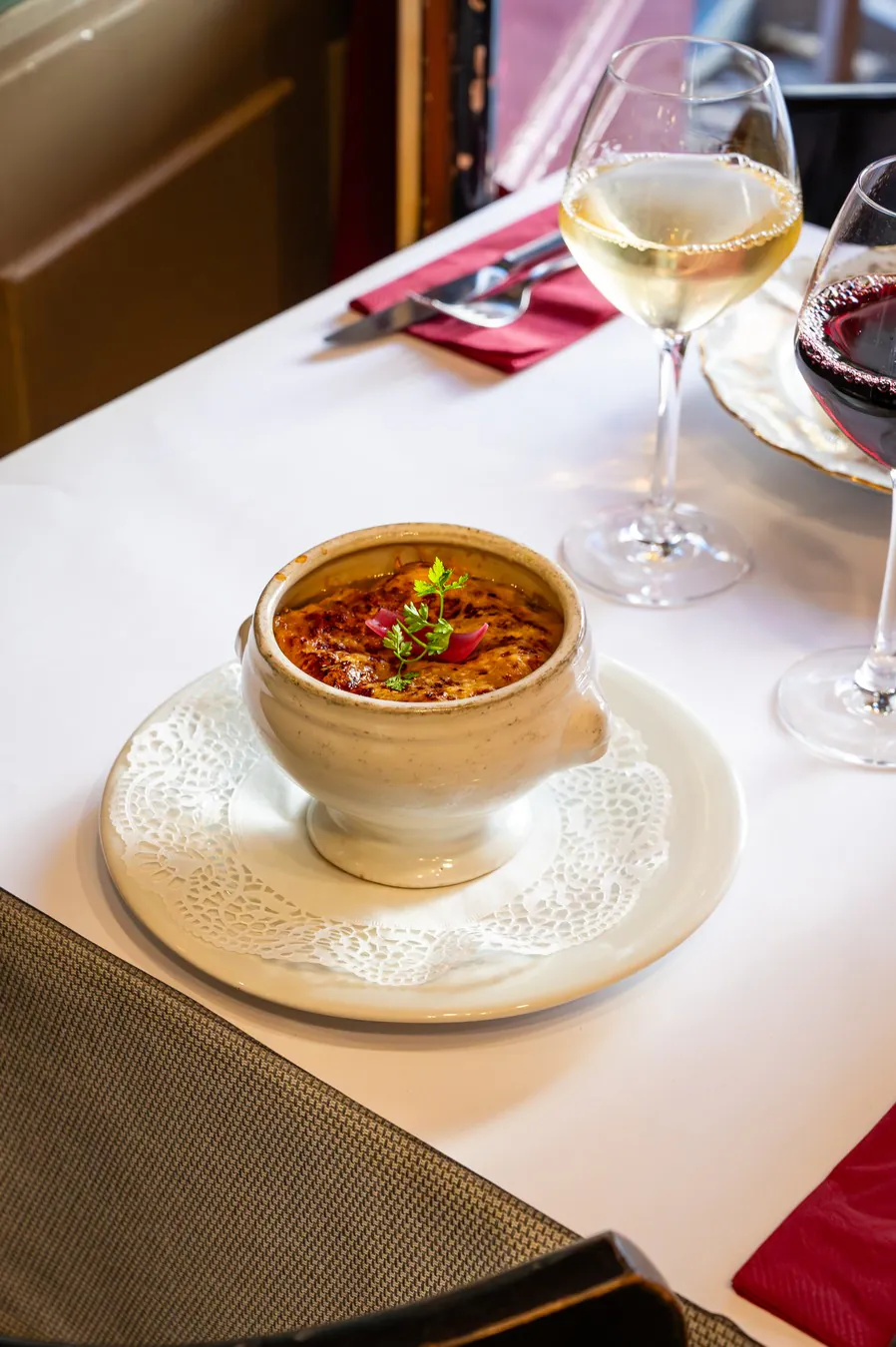 Gratinée lyonnaise in its bowl, on a doily
