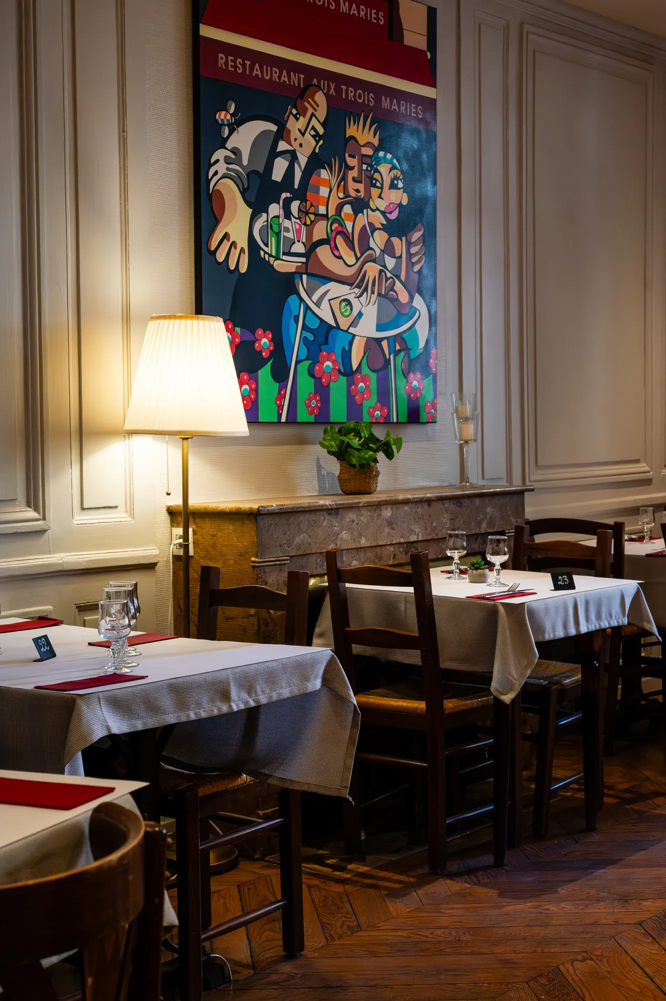Salle du bouchon Aux Trois Maries, table dressée en nappe blanche sous un grand tableau ancien