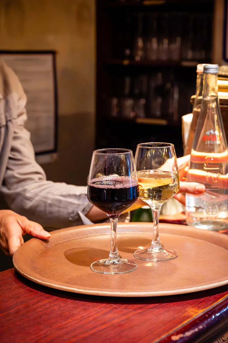 A glass of red and a glass of white brought on a tray