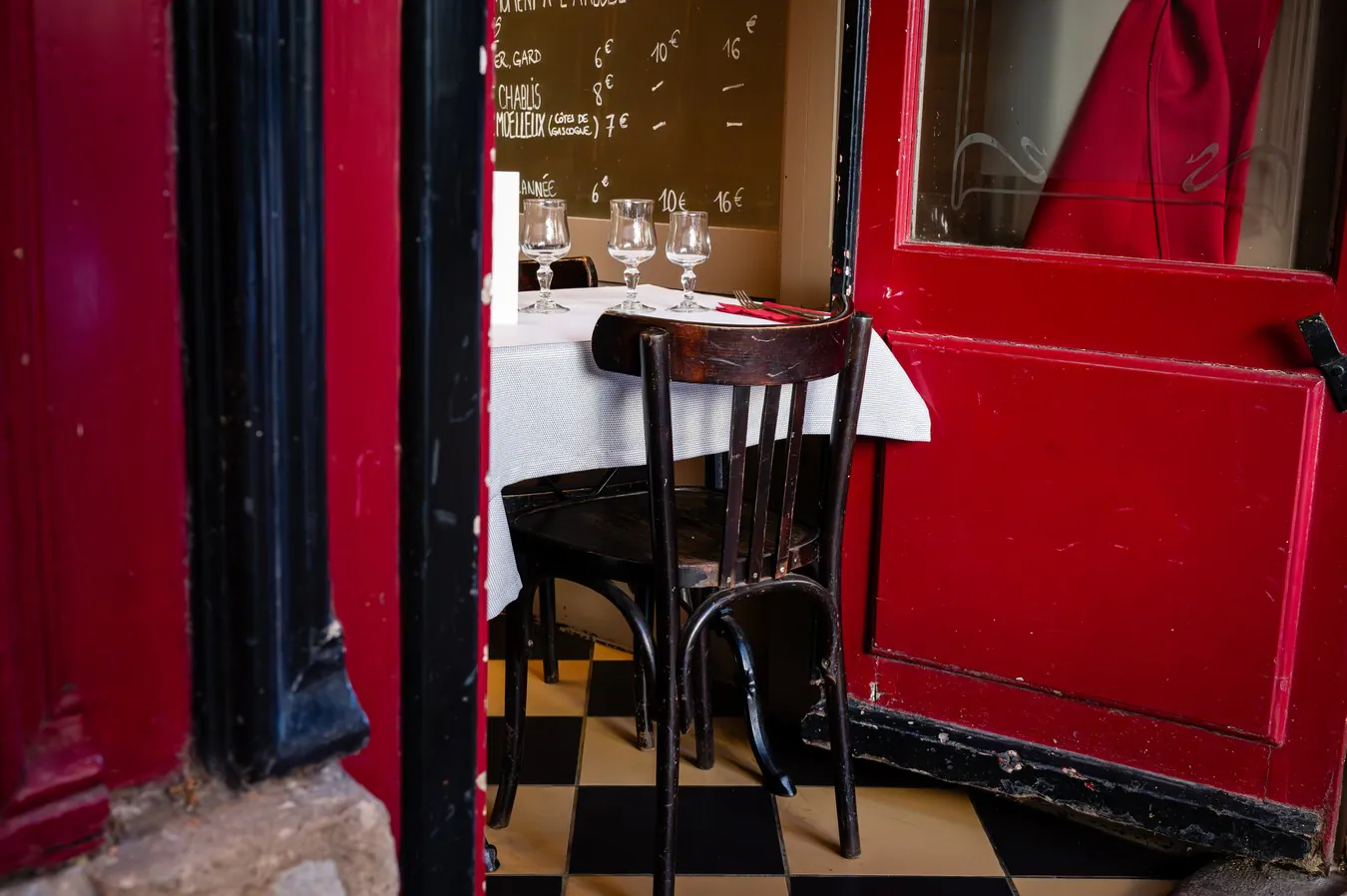 The red door ajar on a laid table and the chequered floor
