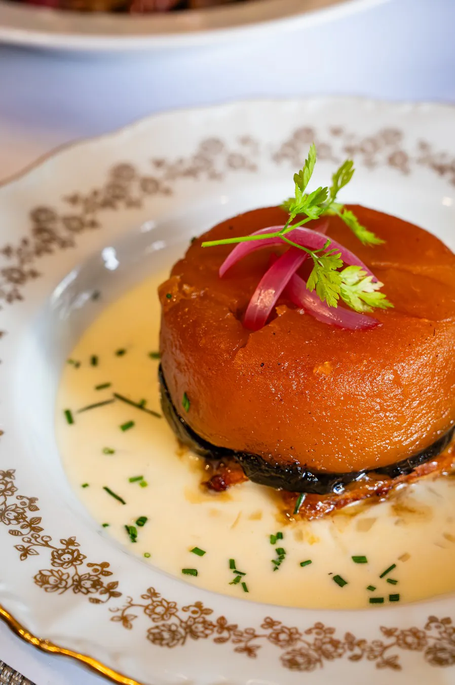 Black pudding tarte Tatin on an antique plate, chive beurre blanc