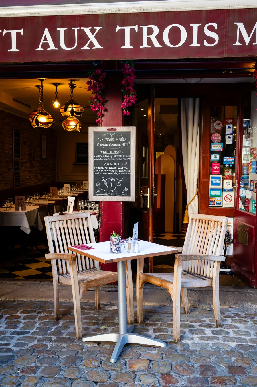 A table laid in front of the open door, the pendant lights on inside