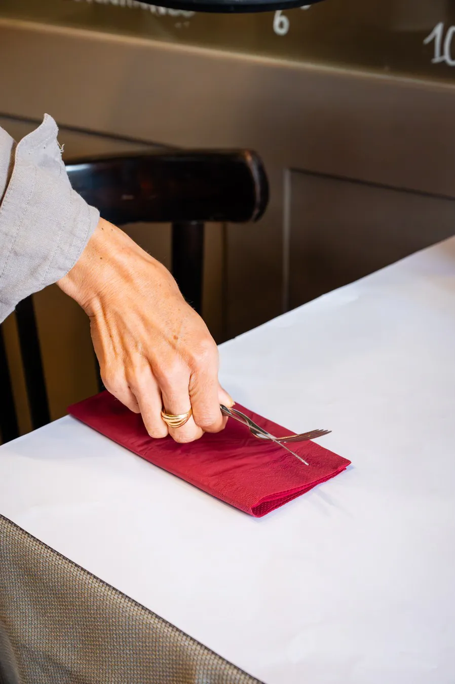 A hand straightening a burgundy napkin on the white tablecloth