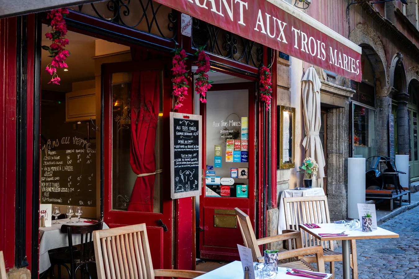 The restaurant entrance, its red woodwork, flowers and slate boards