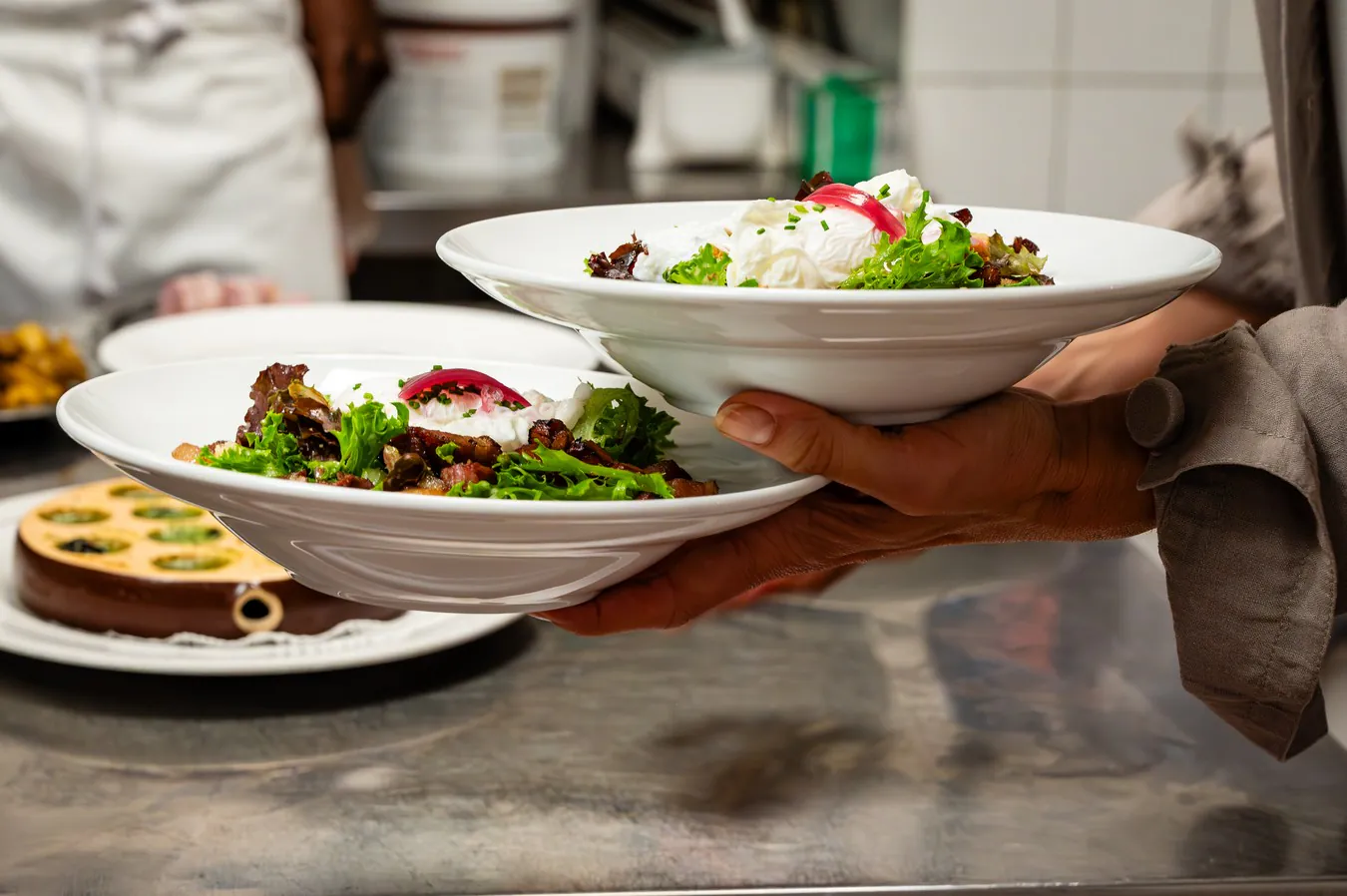 Two Lyonnaise salads held at the pass, ready to go out