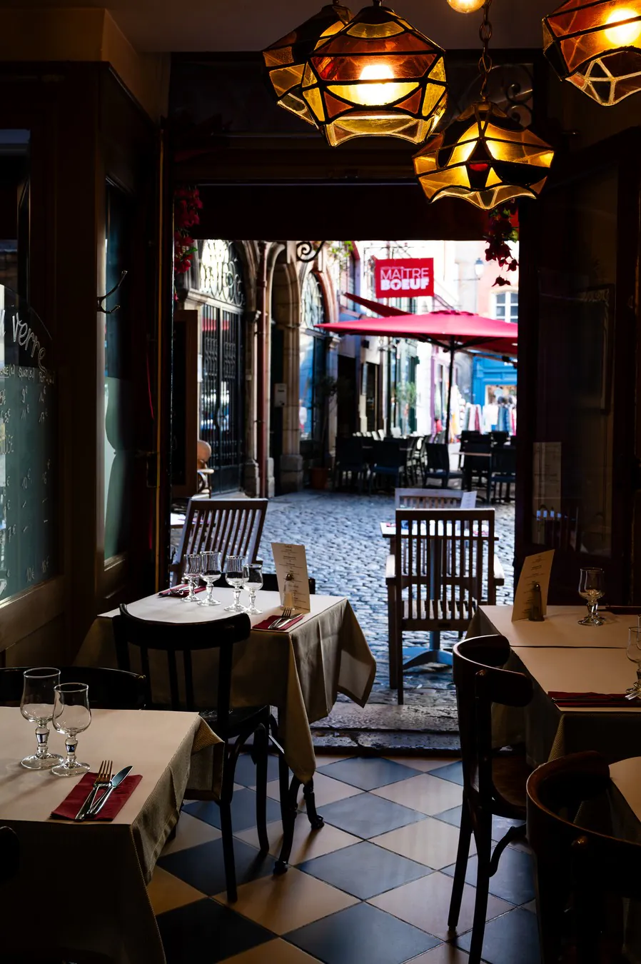 From the dining room, the door open onto the cobbled street, beneath the glass pendant lights