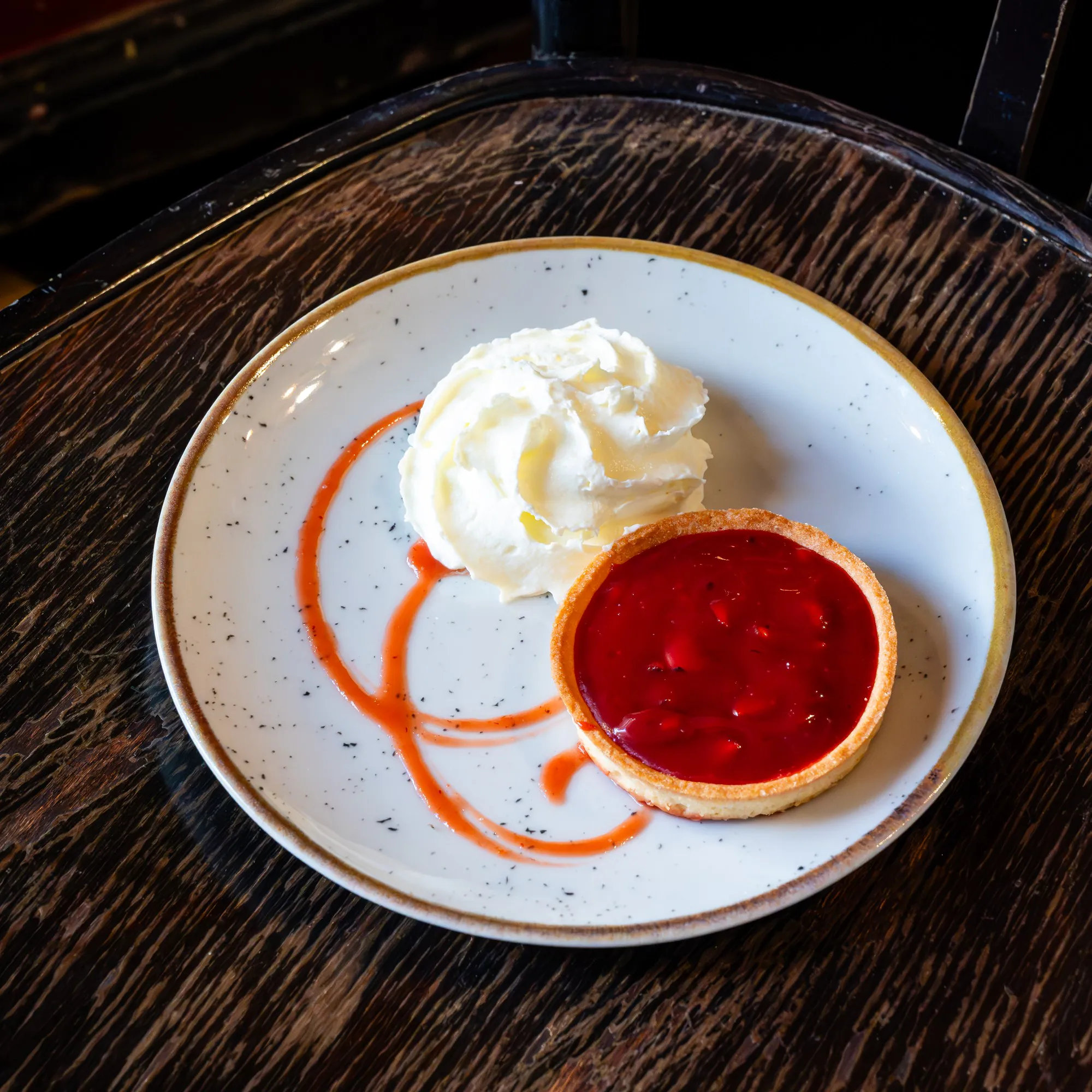 Red-fruit tart with a glossy coulis and a scoop of vanilla ice cream, a festive dessert