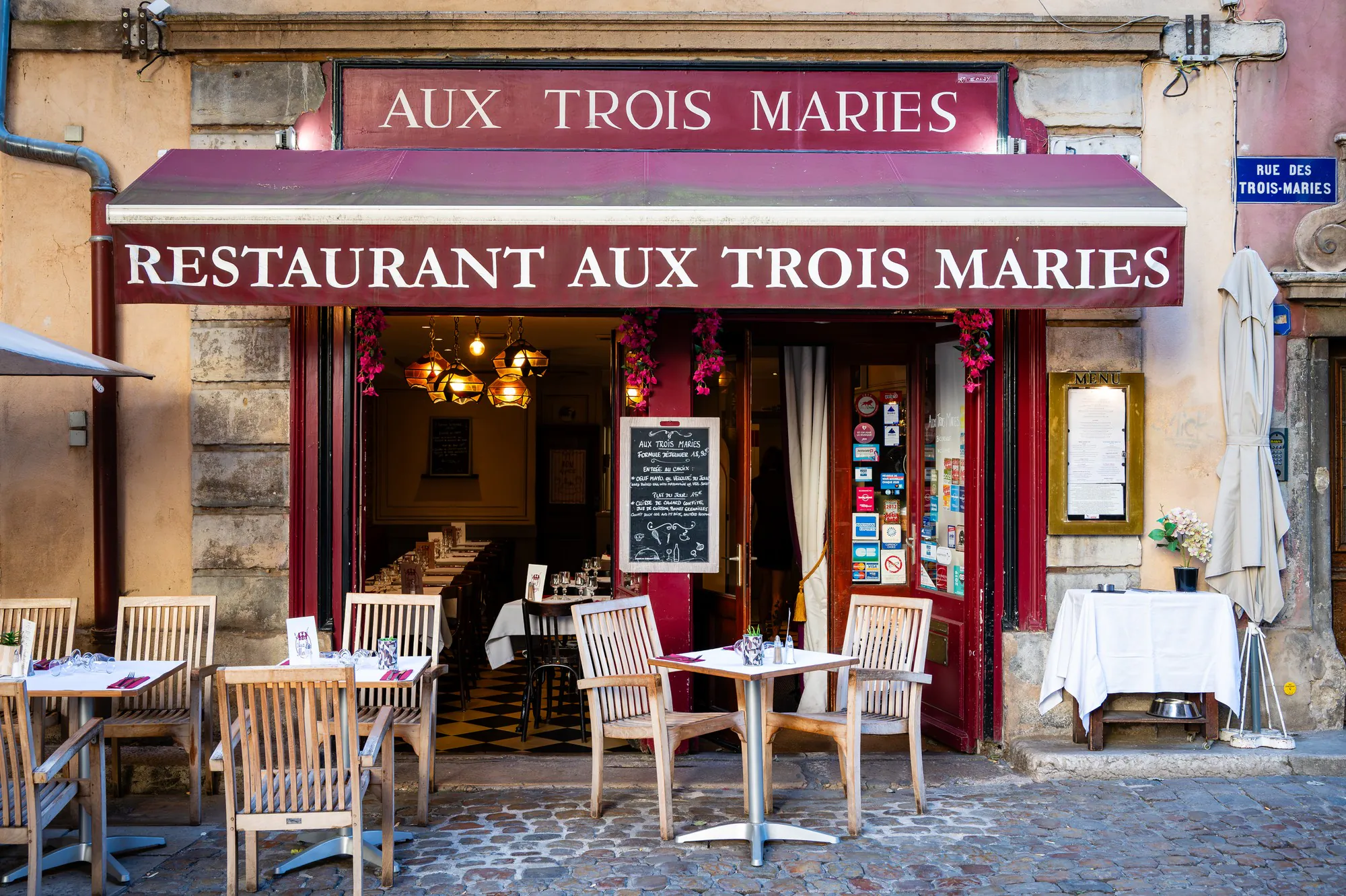 Front of Aux Trois Maries with its red awning and terrace, rue des Trois-Maries