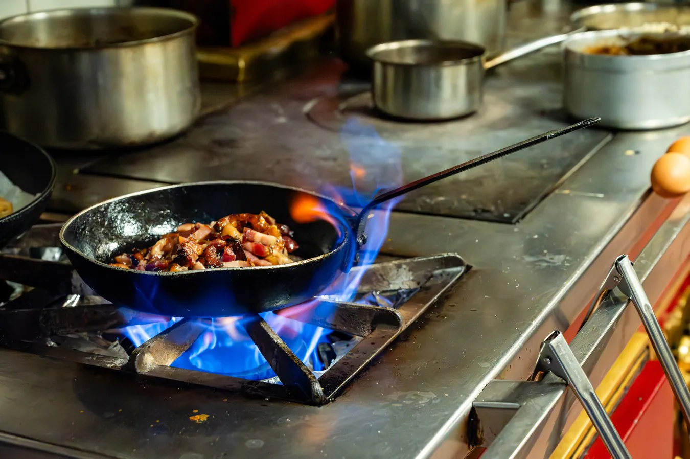A pan over the flame of the range, among the saucepans